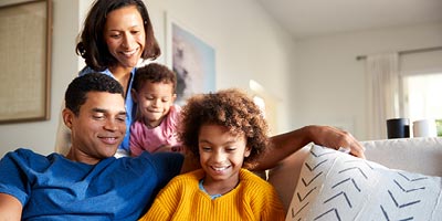 Smiling mom and dad sitting on couch with two children