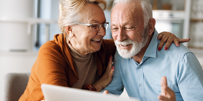 Senior couple looking at laptop, smiling