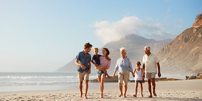 Multi-generational family walking together along the beach.