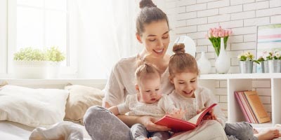 Mom reading to child and baby indicating change that might affect life insurance needs