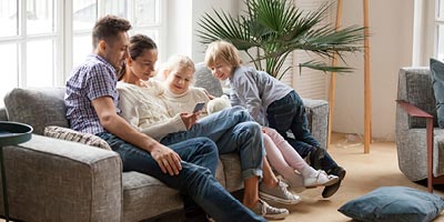 Young family sitting on their couch with the newest baby in mom’s lap. 