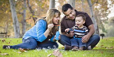 Couple outside blowing bubbles with their baby boy.
