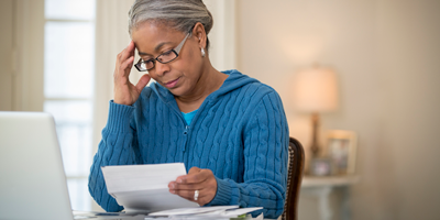 A senior African American woman reviewing her pension paperwork while deciding who to make her beneficiary.