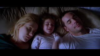 Mom, dad and young daughter in bed right before the alarm goes off in the morning