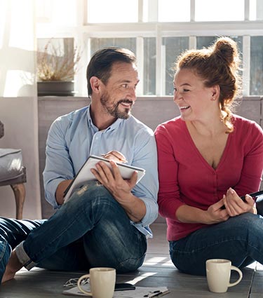 Couple sitting on floor with coffee and notebooks