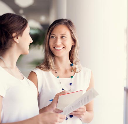 Smiling female coworkers talk in hallway