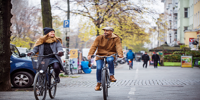 Two young adults biking through a city in the fall