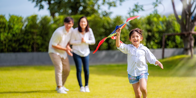 Mom and dad cheering on daughter as she flies a kite