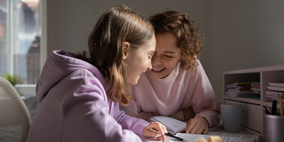 Teenage girl and her mom laugh while doing homework