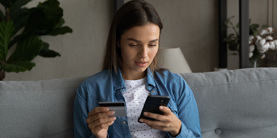 Young woman holding a credit card and looking at her phone