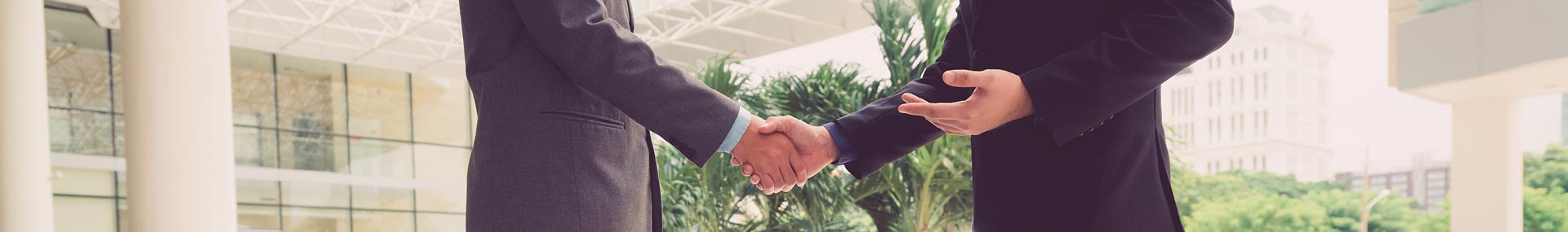 focus of image is on a handshake in an office environment 