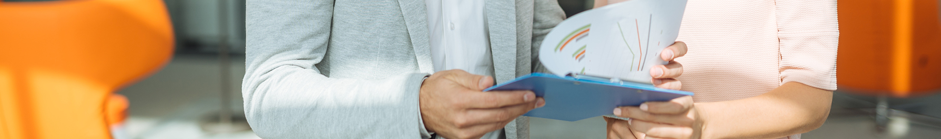 Two businesswomen looking at reports on clipboard.