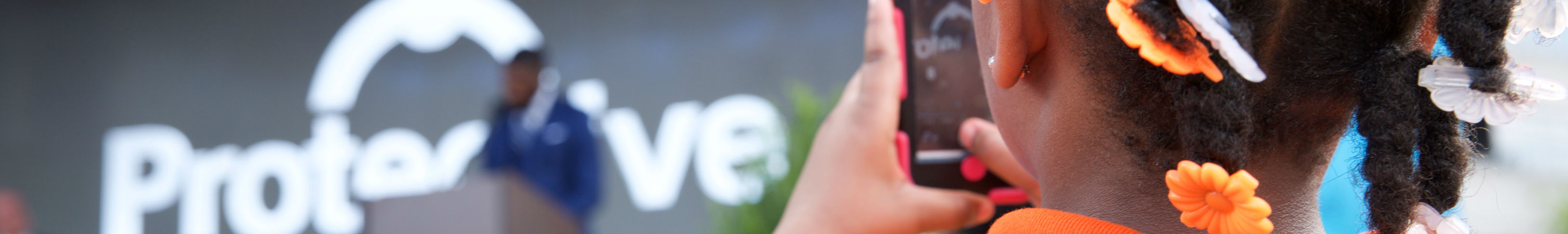 Young girl takes photo of speaker on stage with smartphone