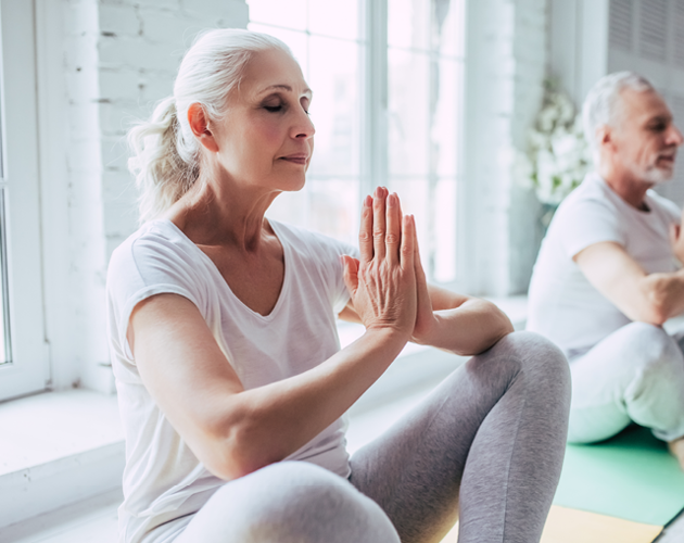 A woman and man practice a yoga pose sitting next to each other