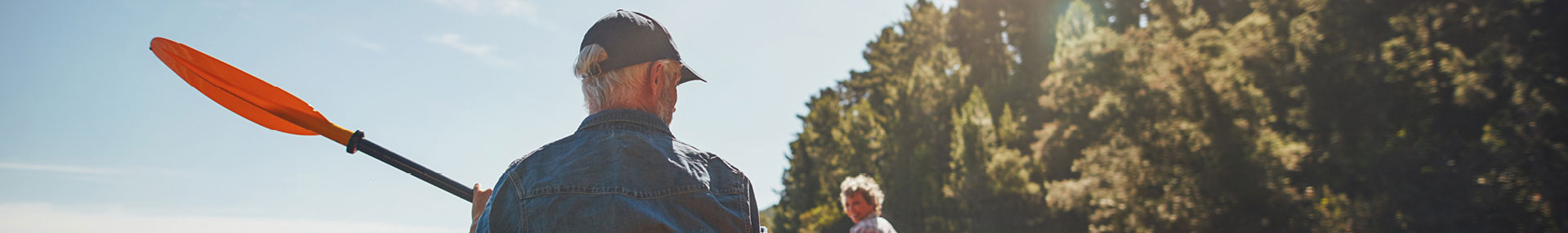 A man kayaks with beautiful trees all around him.