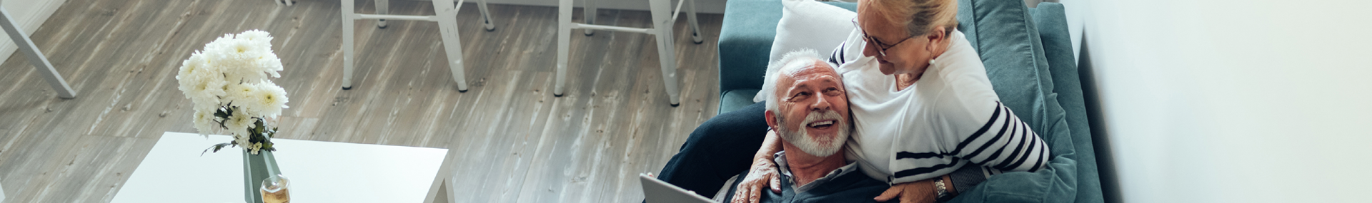 a senior couple relaxing on their couch with a computer.