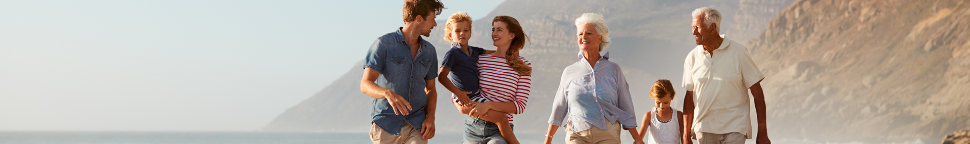 Three generations of family walk along a sandy beach