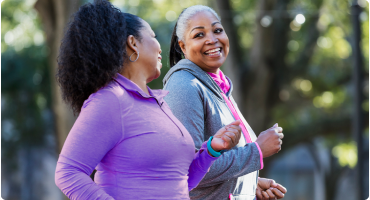 Two women smiling while power walking.