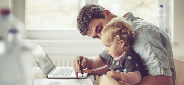 Father and baby sitting at a desk with a laptop