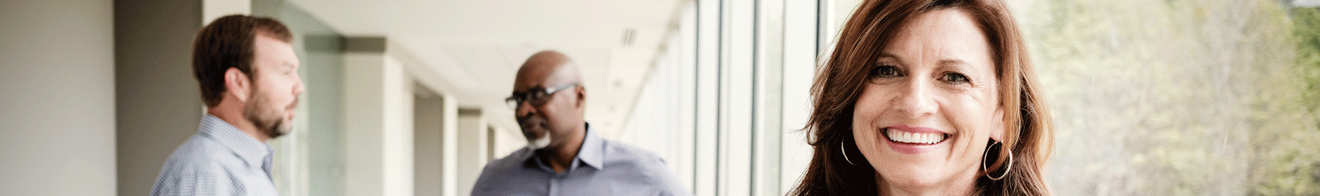 A Protective employee smiles at the camera while coworkers in the background have a discussion