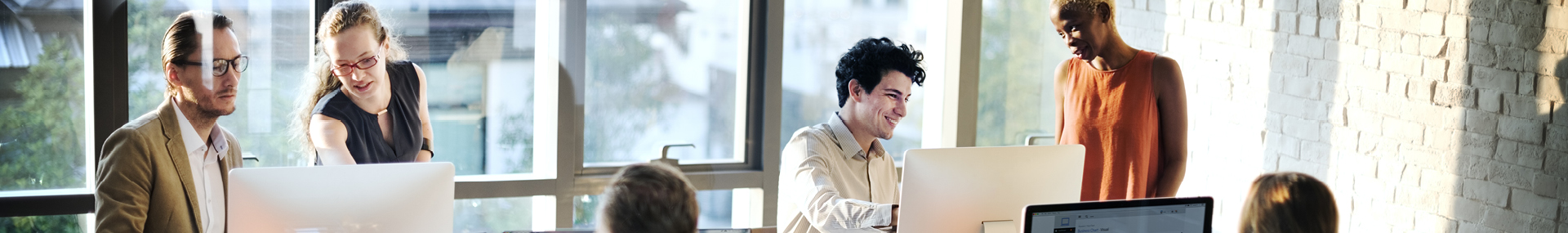 Several professionals are working in front of computers in a modern office environment