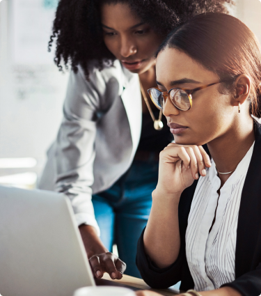Two teammates looking at a laptop together.