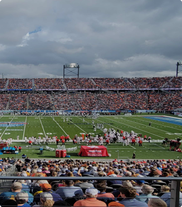 Fans in the stadium watch football players on the field at the Birmingham Bowl.
