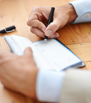 A man's hands writing in a checkbook.