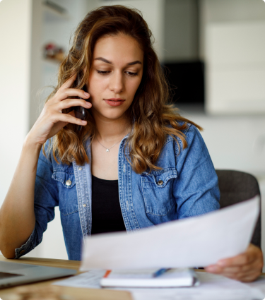 A woman talking on the phone and reviewing documents about closing an Immediate Benefit Account.