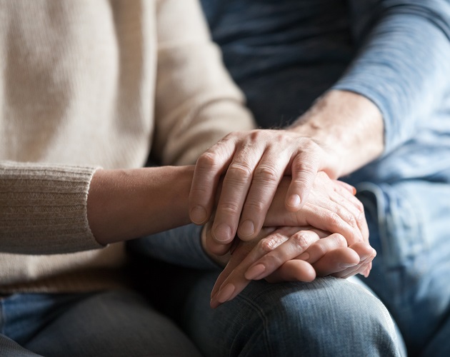 Man comforting woman by placing hand on top of hers