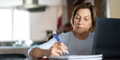 Middle-aged woman using a laptop to check a Protective claim status.