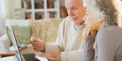 Middle-aged couple using a laptop to update the beneficiary of their Protective life insurance policy.