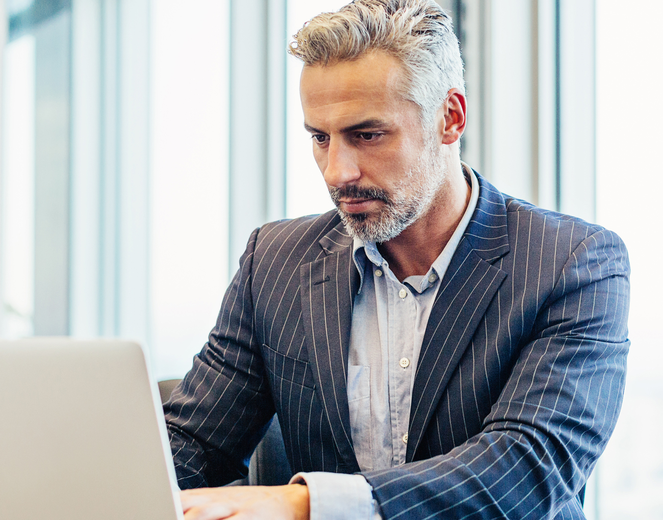 A man works on a laptop while standing.