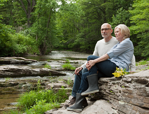Older couple sitting on rock near pond