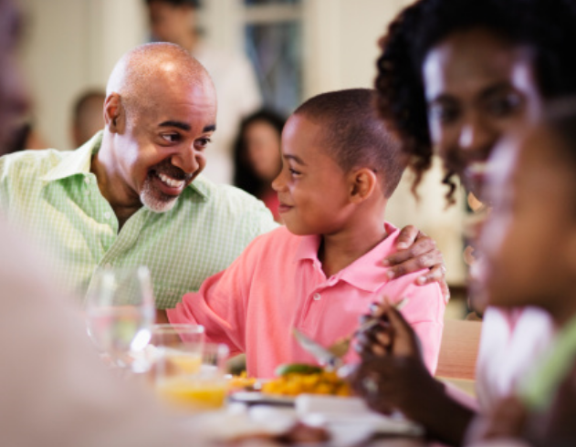 A family smiles while sharing a meal together.