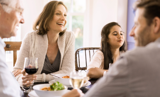 A family smiles while sharing a meal together.