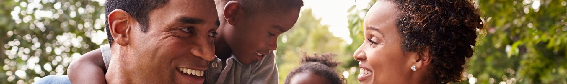 African American family smiles at each other on a walk through the park