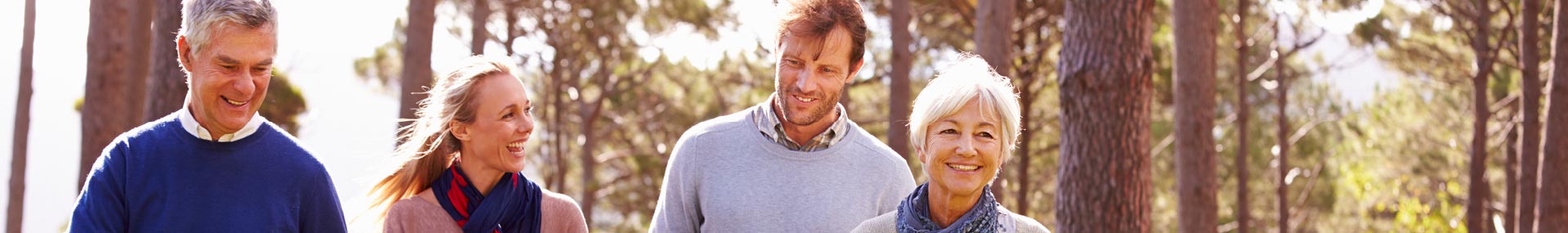 Senior parents and grown children happily walk through the woods together