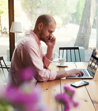 Man using laptop and phone at dining room table