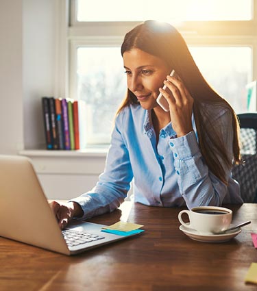 Woman using computer and smartphone in home office