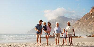  Multi-generational family walking together along the beach.