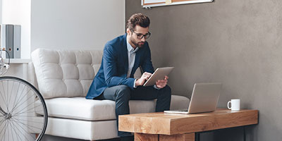 Man in his 30s dressed for work, looking intently at a tablet, as if researching benefits.