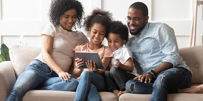 Family on a couch in their living room looking at a tablet to research life insurance companies.