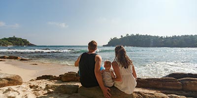 Young family sitting on the beach and looking out over the ocean. 