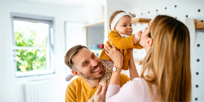 A mom and dad playing with their young newborn in their home