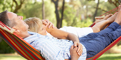 Senior aged couple laying in a hammock together.