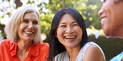 Asian, african-american and caucasian women in their early 50s laughing.