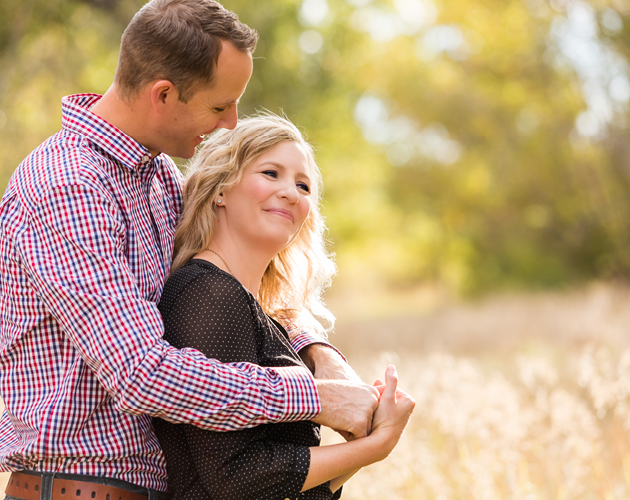 A couple in their thirties embracing surrounded by trees.