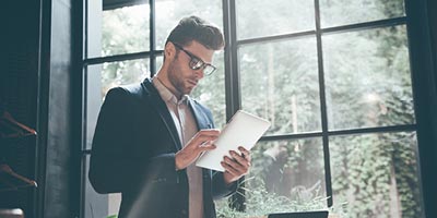 Thirty-something man with glasses reviewing his life insurance policy on a computer tablet