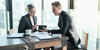 Professional man and woman looking at a tablet, as if reviewing insurance options.